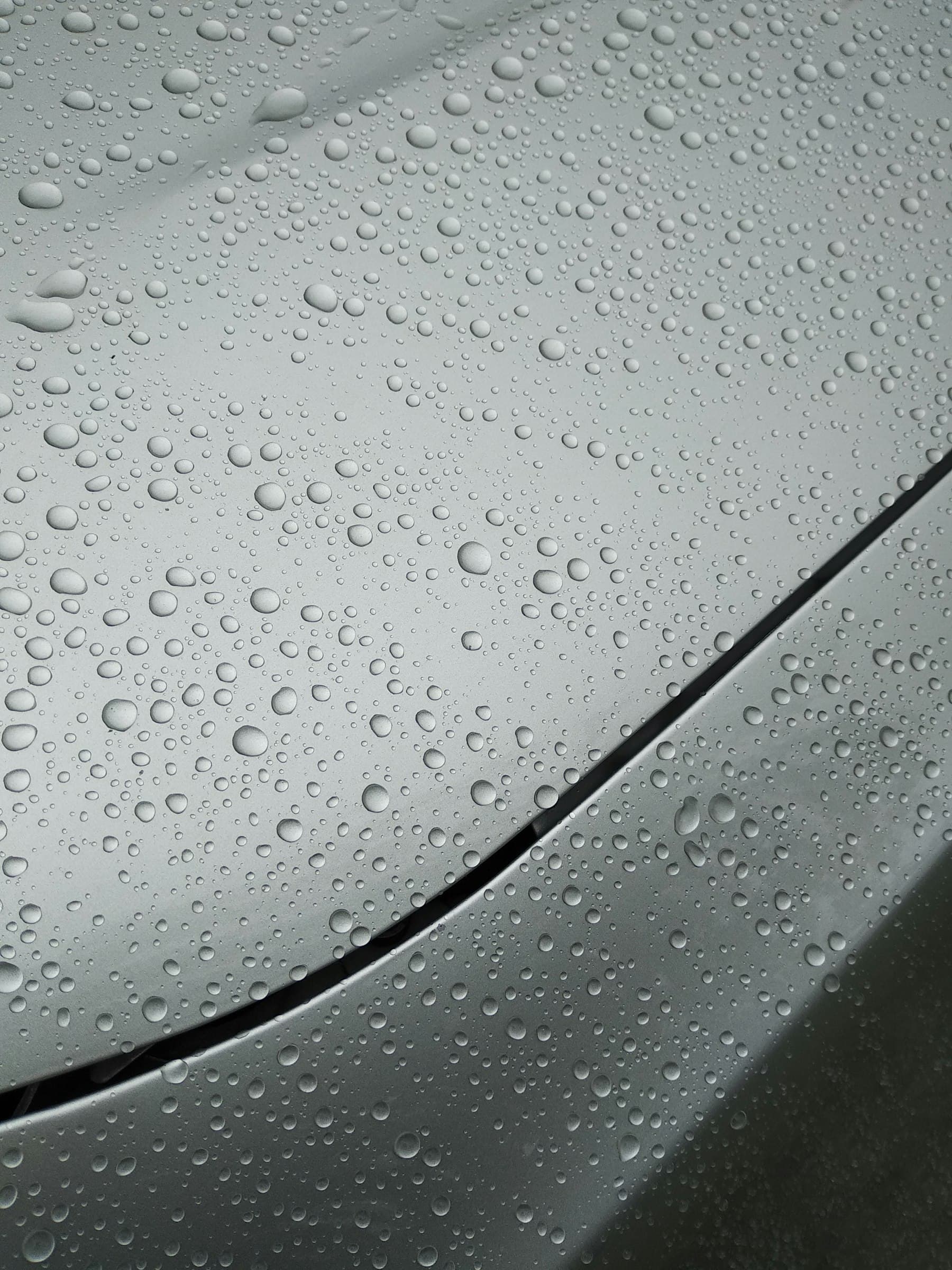 Water beading on a coated metallic grey car bonnet