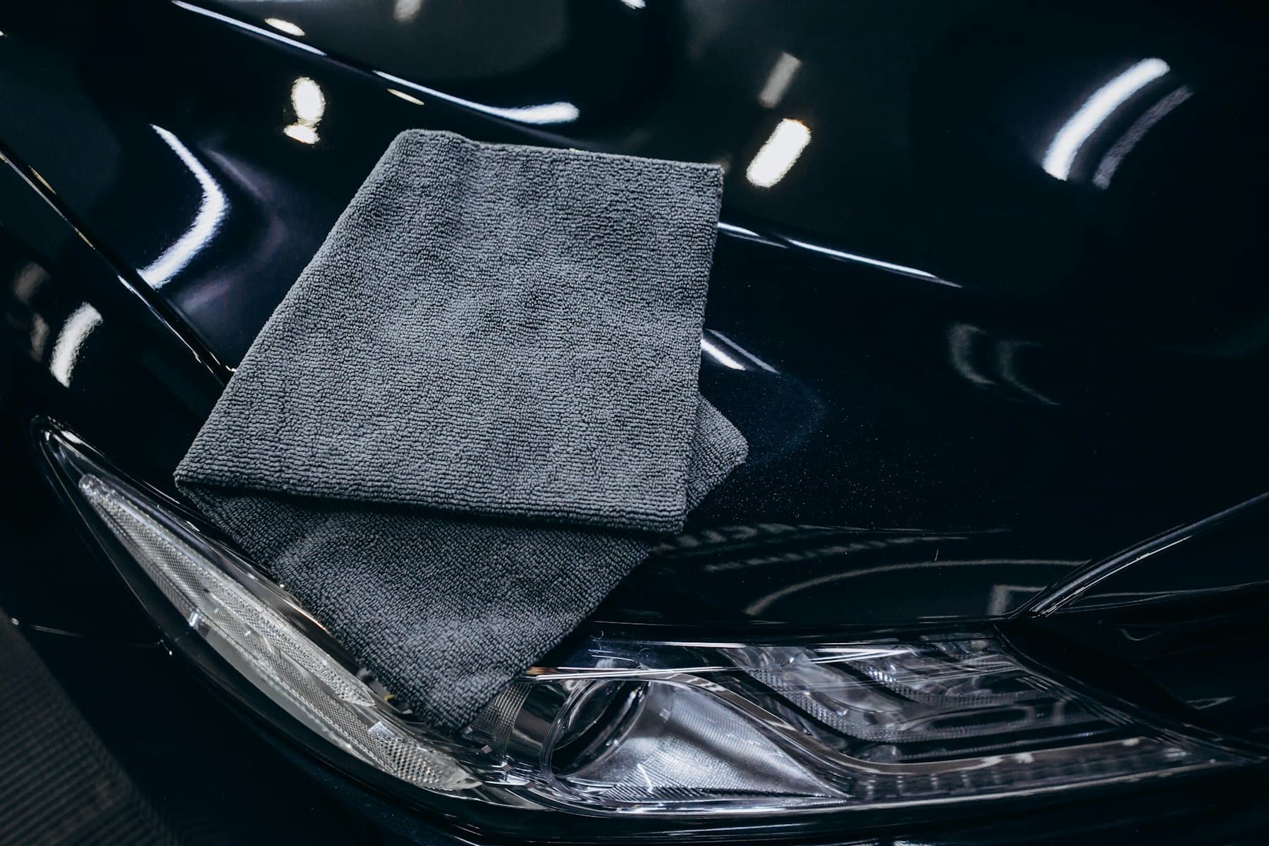 Folded microfibre cloth resting on a glossy black car bonnet